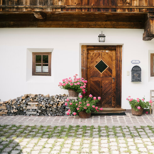 Rustikales Zuhause mit blühenden Töpfen und Holzdepot Gästehäuser